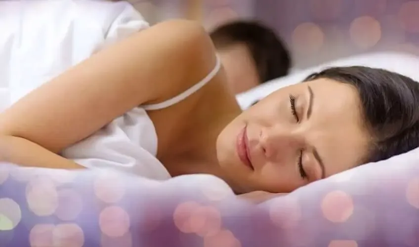 A person lying on a mattress holding their lower back